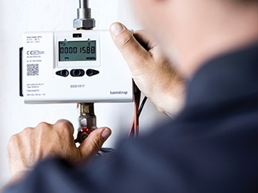 A man finalizing the setup of a Multical 603 Heat and Cooling meter.